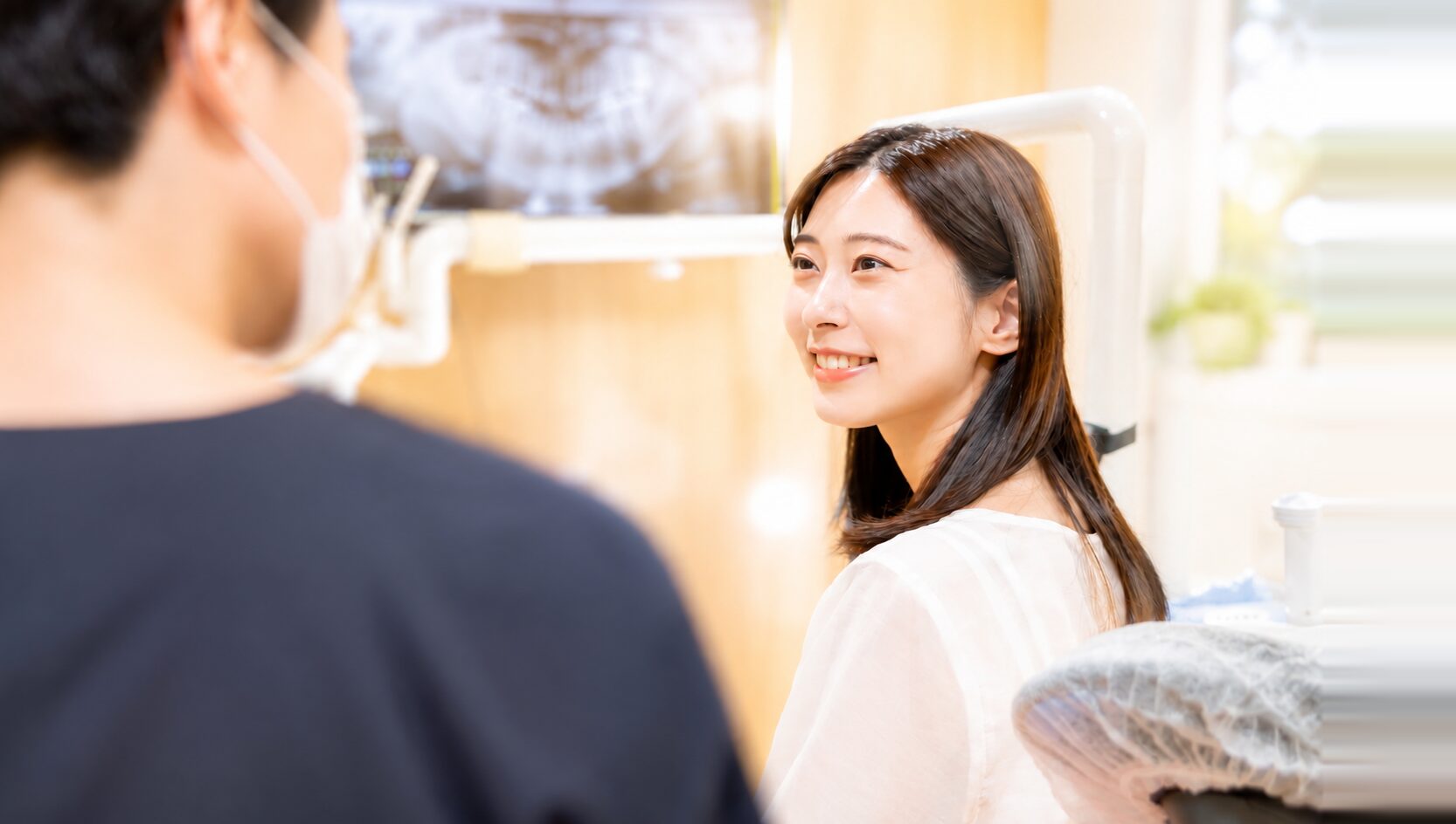 歯科医院で歯科医師とパノラマX線写真を見ながら、笑顔で相談する女性の患者